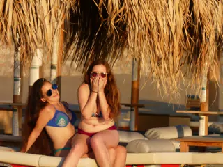 Teen Girls Sitting on Lap on Palaiochora Beach on Crete