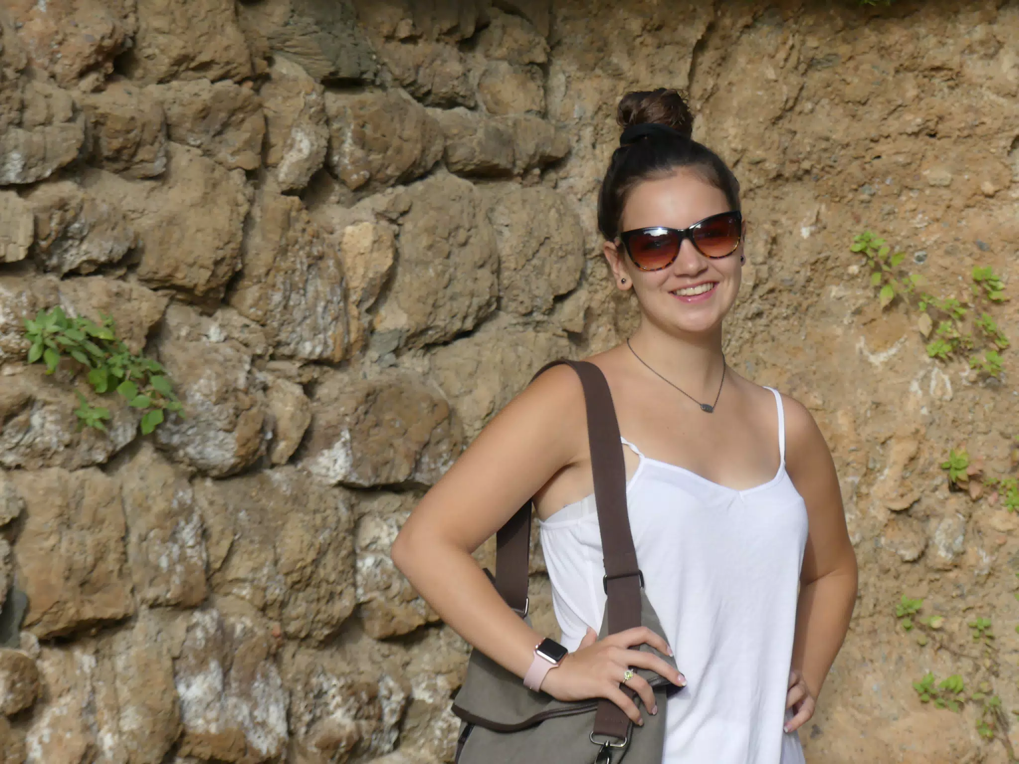 Brunette Teen Model in White Camisole Posing Against Stone Wall at Park Guell in Barcelona