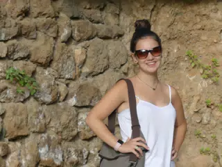 Brunette Teen Model in White Camisole Posing Against Stone Wall at Park Guell in Barcelona