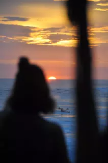 Girl Watching Sunset from Simple Beach Lodge