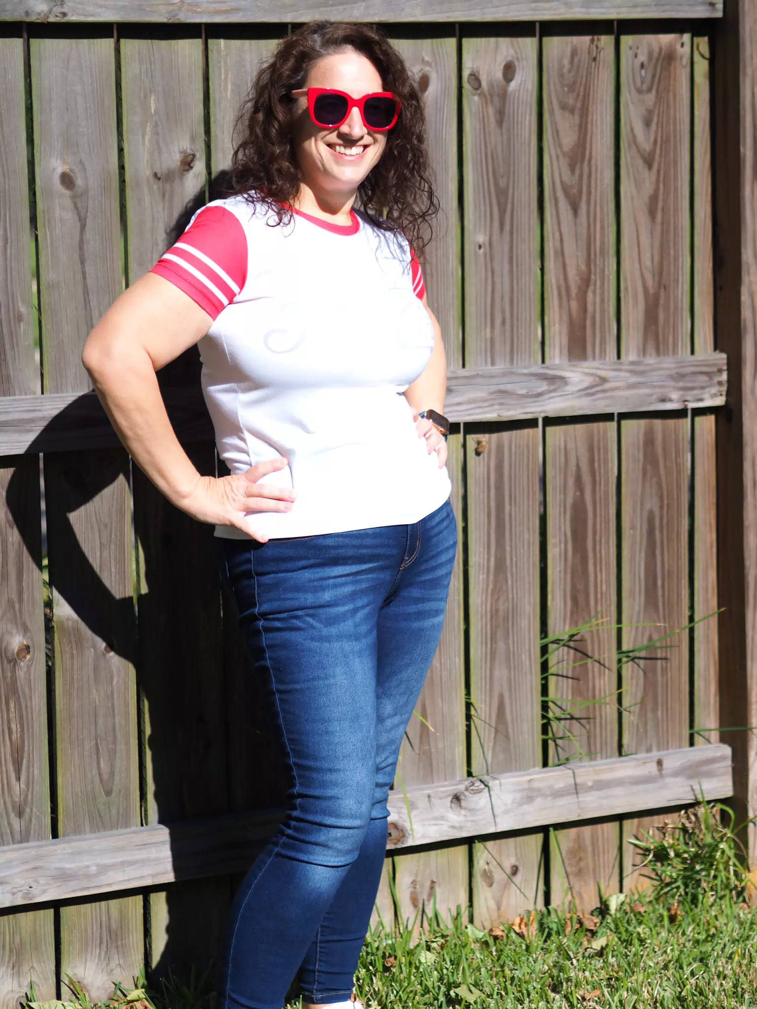Dominica in Red Sunglasses and Jeans Against Fence