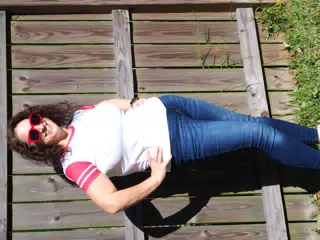Dominica in Red Sunglasses and Jeans Against Fence
