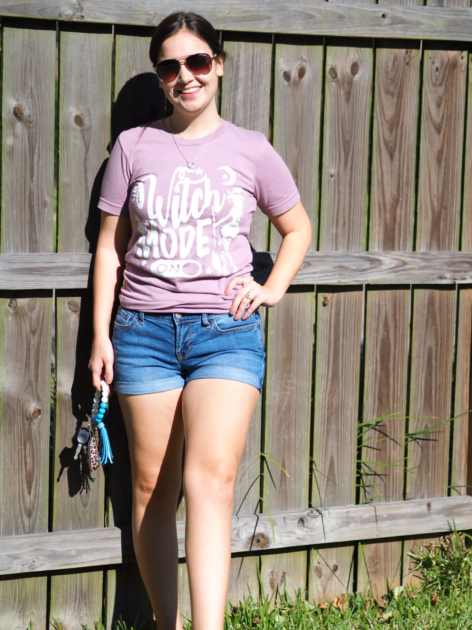 Emily Standing with Keys in Shorts by Wooden Fence